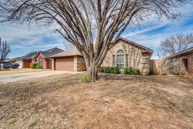 view of front facade featuring an attached garage, fence, concrete driveway, and brick siding