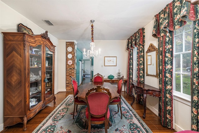 dining space with a chandelier, dark wood-style flooring, visible vents, and ornamental molding