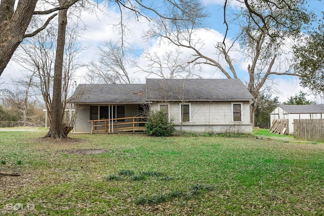 rear view of house with a yard and fence