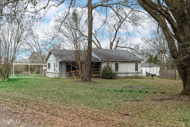 rear view of house featuring fence and a lawn