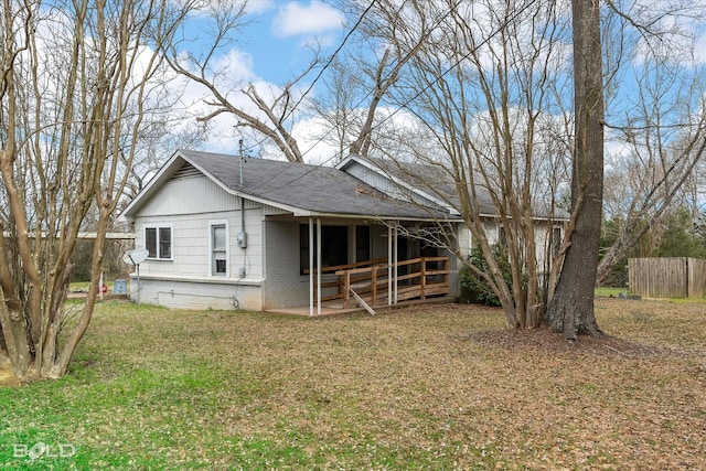 bungalow-style house featuring brick siding, roof with shingles, a front yard, and fence