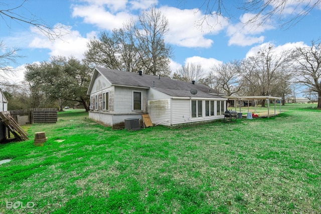 back of property featuring a shingled roof, central AC, and a lawn