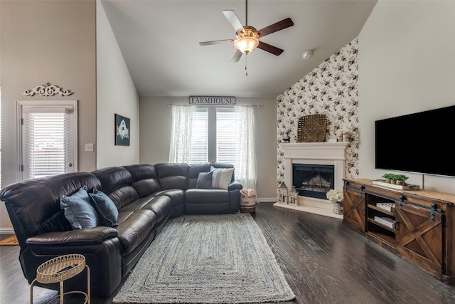 living area featuring a fireplace with raised hearth, dark wood-type flooring, ceiling fan, high vaulted ceiling, and baseboards