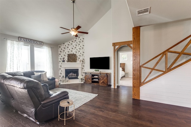 living room featuring visible vents, a ceiling fan, dark wood-style floors, a fireplace, and high vaulted ceiling