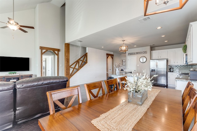 dining room with dark wood finished floors, recessed lighting, visible vents, a towering ceiling, and ceiling fan with notable chandelier