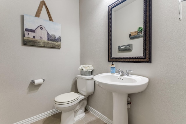 bathroom featuring tile patterned flooring, baseboards, and toilet