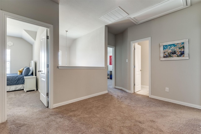 hall featuring attic access, baseboards, vaulted ceiling, and carpet flooring