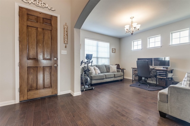 living room featuring arched walkways, dark wood-type flooring, baseboards, and an inviting chandelier