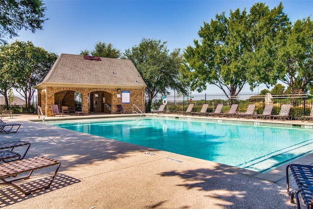 pool with an outbuilding, a patio area, and fence