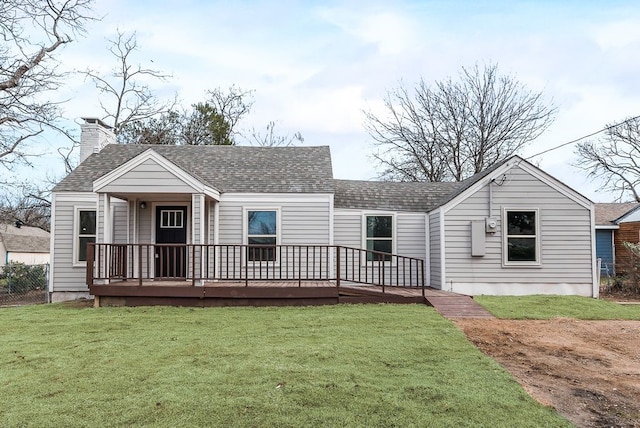 view of front facade with a chimney, roof with shingles, a front yard, and fence