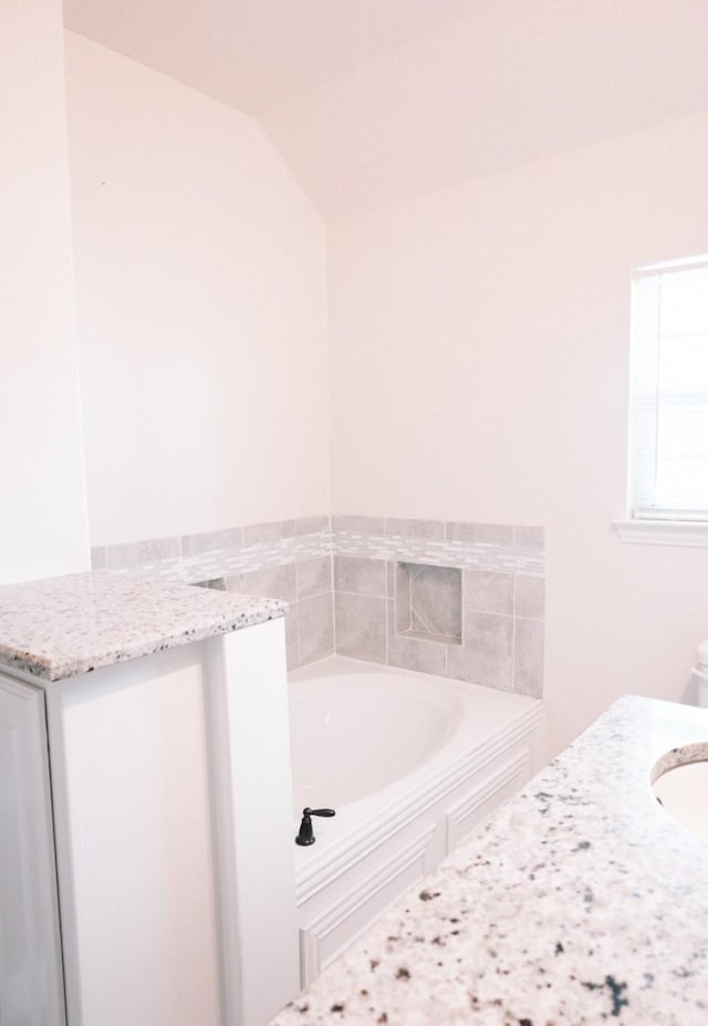 full bathroom with vaulted ceiling, a sink, and a bath