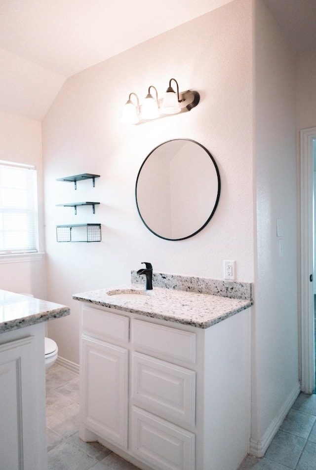 bathroom with toilet, vaulted ceiling, vanity, and baseboards