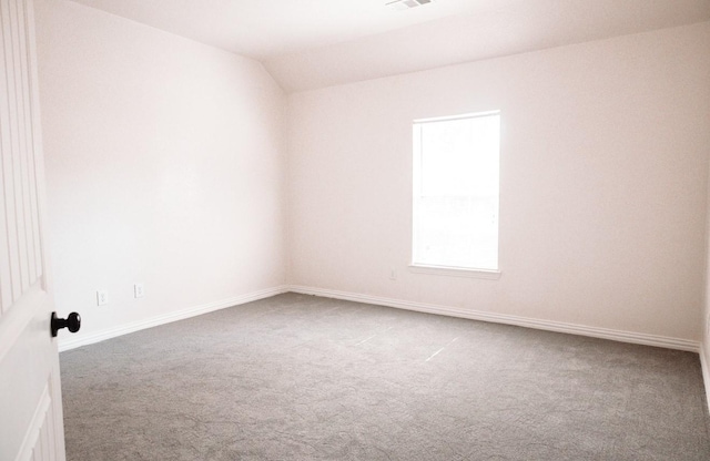 carpeted spare room with vaulted ceiling, visible vents, and baseboards