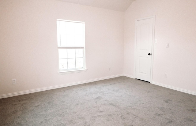 carpeted spare room with lofted ceiling and baseboards