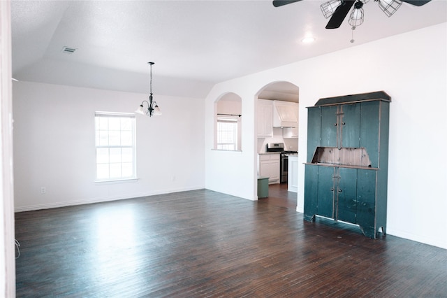 unfurnished living room featuring arched walkways, dark wood finished floors, visible vents, ceiling fan, and baseboards