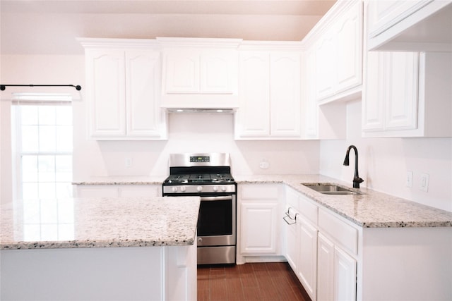 kitchen with dark wood finished floors, stainless steel range with gas cooktop, white cabinets, and a sink