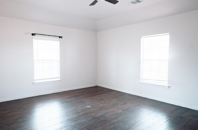 unfurnished room with dark wood-style floors, ceiling fan, visible vents, and baseboards