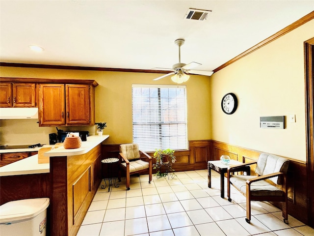 interior space with visible vents, ornamental molding, wainscoting, ceiling fan, and light tile patterned flooring