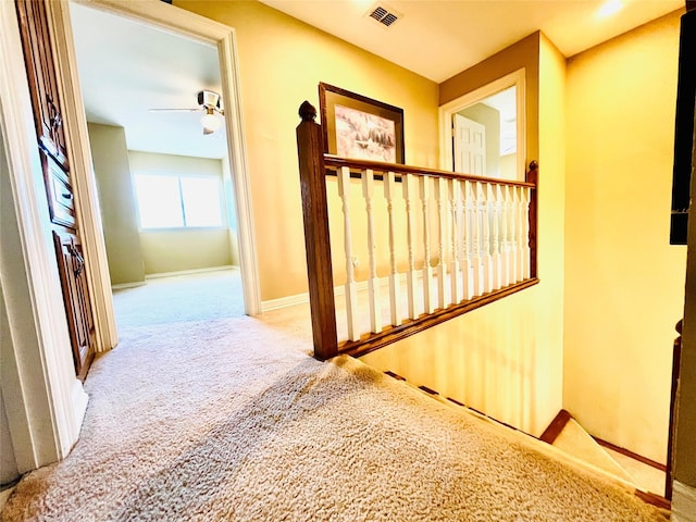 corridor with carpet, visible vents, and baseboards