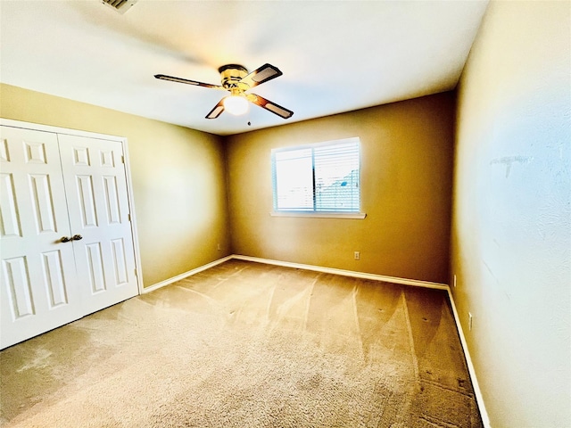 carpeted empty room with ceiling fan and baseboards