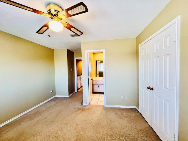 unfurnished bedroom with light carpet, baseboards, a closet, and ensuite bathroom