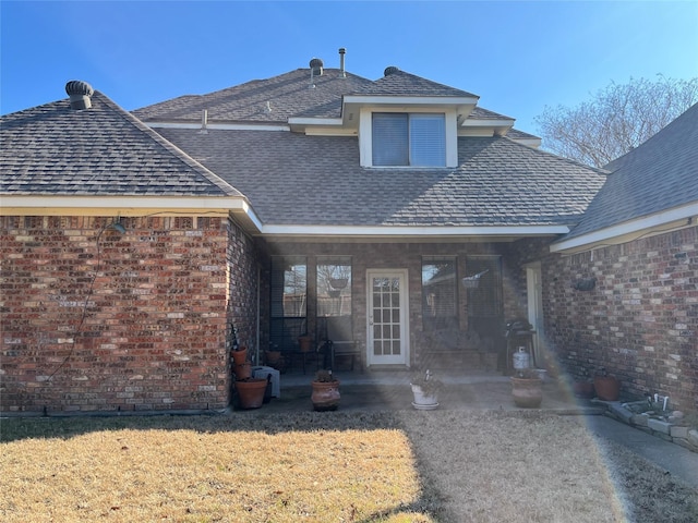 rear view of property with a yard, brick siding, and a patio area