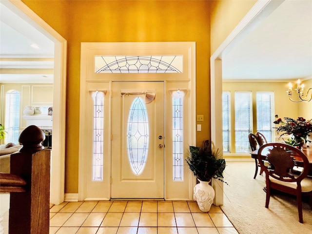 entryway featuring ornamental molding, light tile patterned floors, and an inviting chandelier