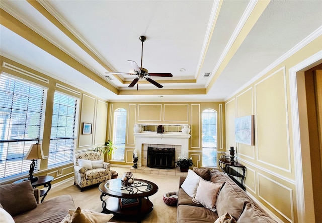 living room featuring a fireplace, ornamental molding, a decorative wall, and a wealth of natural light