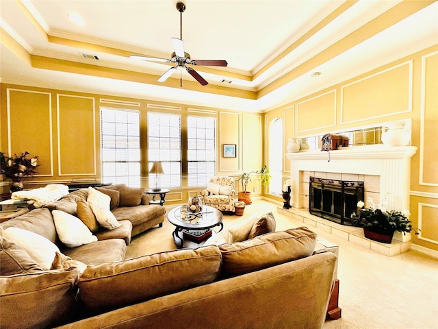 living area featuring visible vents, a fireplace, a tray ceiling, and a decorative wall