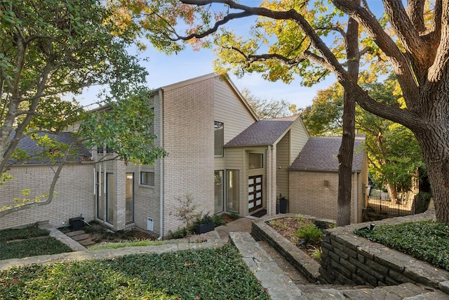 view of front of property with a shingled roof and brick siding