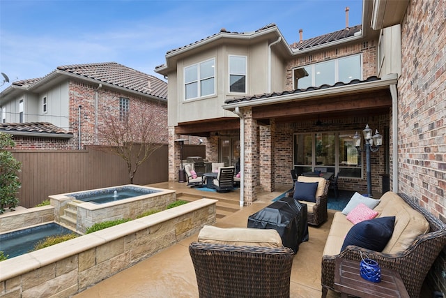 back of house featuring a patio, an in ground hot tub, brick siding, outdoor lounge area, and fence