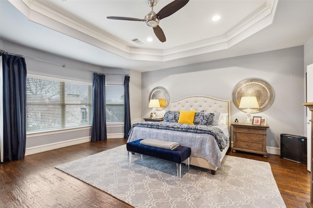 bedroom featuring a raised ceiling, visible vents, ornamental molding, wood finished floors, and baseboards