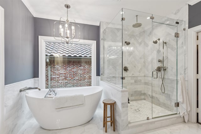 full bathroom with marble finish floor, a notable chandelier, a soaking tub, ornamental molding, and a shower stall