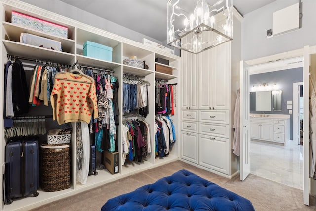 walk in closet with a notable chandelier, a sink, and light colored carpet