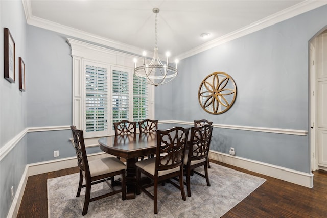 dining space featuring arched walkways, crown molding, an inviting chandelier, wood finished floors, and baseboards