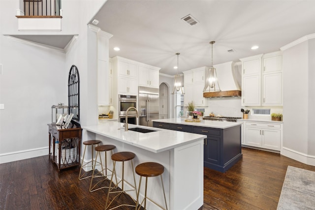 kitchen featuring arched walkways, appliances with stainless steel finishes, custom exhaust hood, and white cabinets