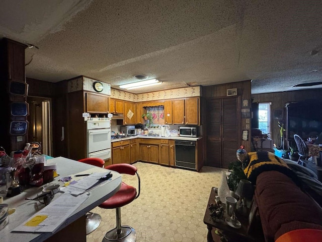 kitchen featuring black dishwasher, stainless steel microwave, brown cabinets, oven, and light countertops