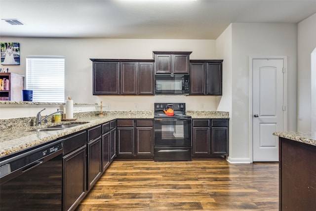 kitchen with dark wood-style floors, light stone countertops, dark brown cabinets, black appliances, and a sink