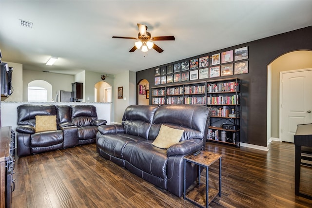 living room with arched walkways, wood finished floors, visible vents, and baseboards