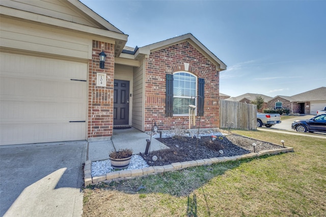 view of exterior entry with brick siding, a lawn, and an attached garage