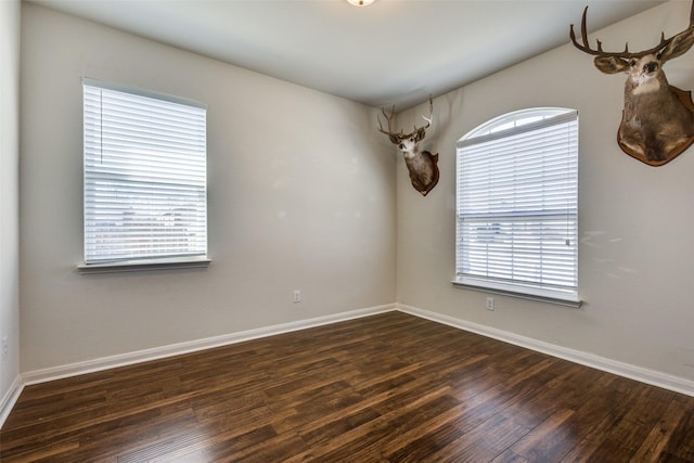 spare room with dark wood-type flooring and baseboards