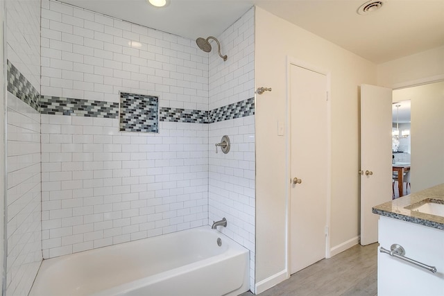 bathroom with visible vents, vanity, wood finished floors,  shower combination, and baseboards