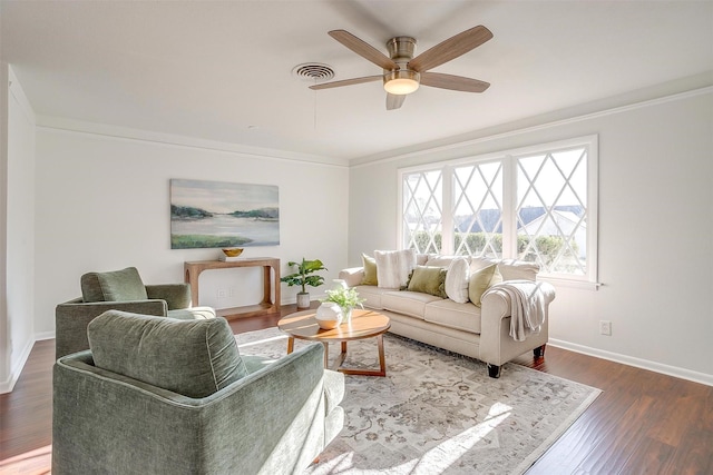 living room with ornamental molding, wood finished floors, visible vents, and baseboards