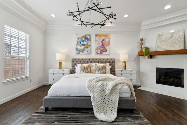 bedroom featuring a tile fireplace, crown molding, baseboards, and wood finished floors