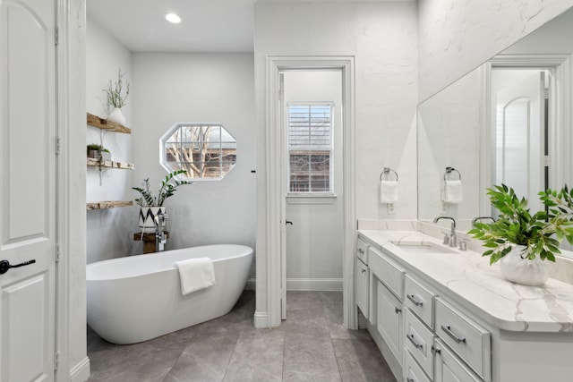 bathroom featuring recessed lighting, a freestanding tub, vanity, and baseboards