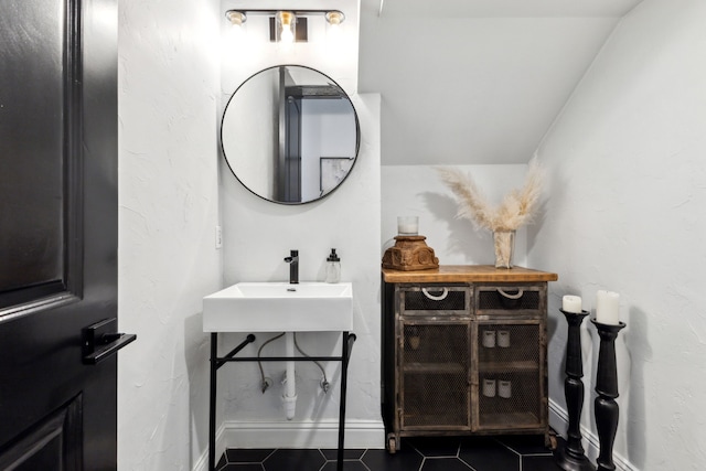 bathroom featuring baseboards, a sink, and tile patterned floors