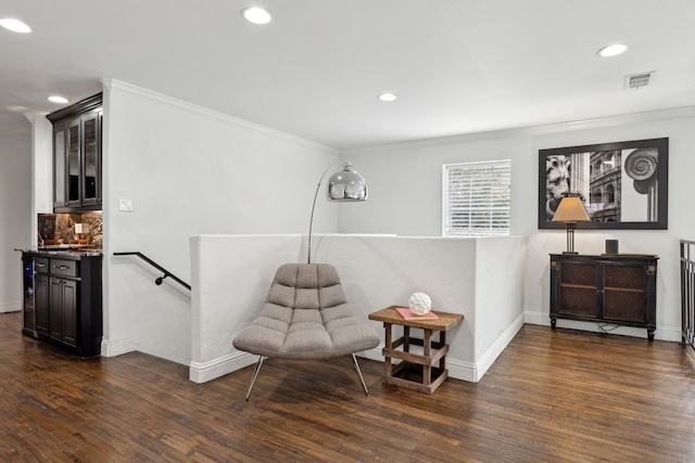 living area with baseboards, visible vents, dark wood finished floors, crown molding, and an upstairs landing