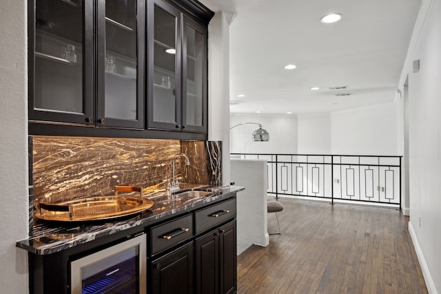 bar with indoor wet bar, dark wood finished floors, decorative backsplash, ornamental molding, and a sink