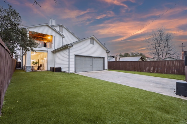 back of property with a balcony, a garage, fence, a yard, and concrete driveway