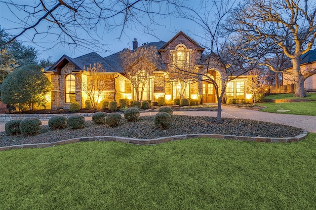 view of front facade with stone siding, brick siding, a chimney, and a front lawn